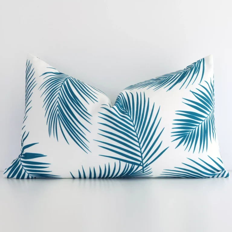 A pretty teal palm printed outdoor cushion cover is shown against a white wall. It features a rectangle shape.