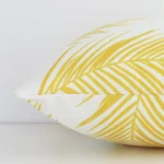 An outdoor yellow palm printed cushion cover shown laying on its side. The rectangle size is shown side on.