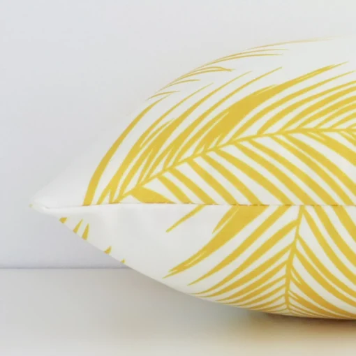An outdoor yellow palm printed cushion cover shown laying on its side. The rectangle size is shown side on.