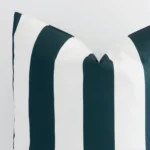 The corner of this green outdoor cushion is shown close up. The finer detail of its large design and striped decorative finish can be seen.