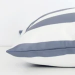 Grey stripe cushion cover laying sideways against white wall. The large size and outdoor material are shown highlighting the seams.
