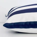 Striped navy cushion laid horizontally. This perspective shows the edge of the outdoor fabric and its large shape.
