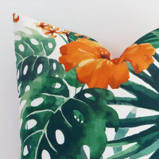 Corner section image showing features of square orange cushion that has a floral motif on its linen fabric.