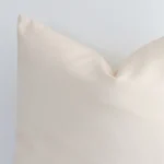 Close range image of beige solid-coloured cushion. The square size and outdoor material can be seen in detail.