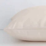Side angle shot of outdoor square cushion cover. The beige hue and solid colour stye are shown along its seams.