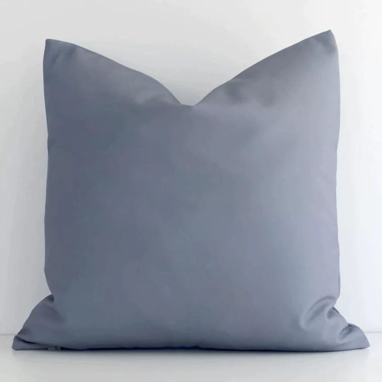 Grey solid-coloured cushion cover sits against a white wall. It is constructed from a superior looking outdoor material and has square shape.
