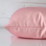The seams of this outdoor square cushion cover in pink are shown.