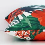A red floral cushion positioned on its back panel. The shot shows a lateral view of the outdoor fabric and its square shape.