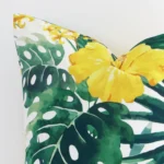 A yellow outdoor cushion cover’s corner is shown in more detail. It is possible to see the square design and floral decorative finish in much more detail.