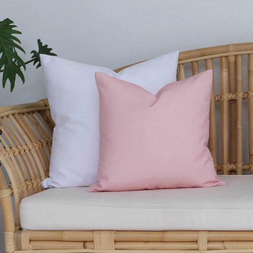 An outdoor scene with a chair hosting pink outdoor cushions.