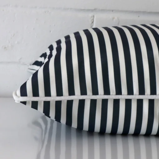 A square navy blue cushion cover laying flat. This viewpoint highlights the striped style and outdoor fabric from a side position.