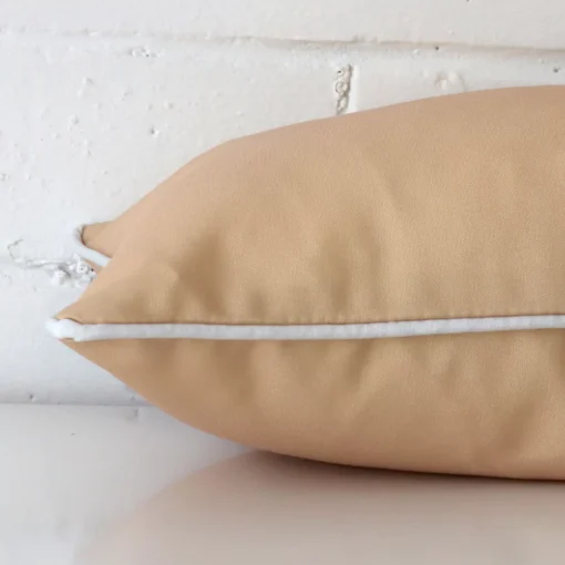 A side shot of an outdoor cushion cover. The angle shows the edge of the rectangle shape and the beige tone.