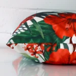 A square floral cushion cover is laid flat. This angle shows the side of the outdoor fabric up close.