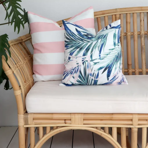 Cozy pink outdoor couch cushions nestled amidst the lush greenery of the outdoors.