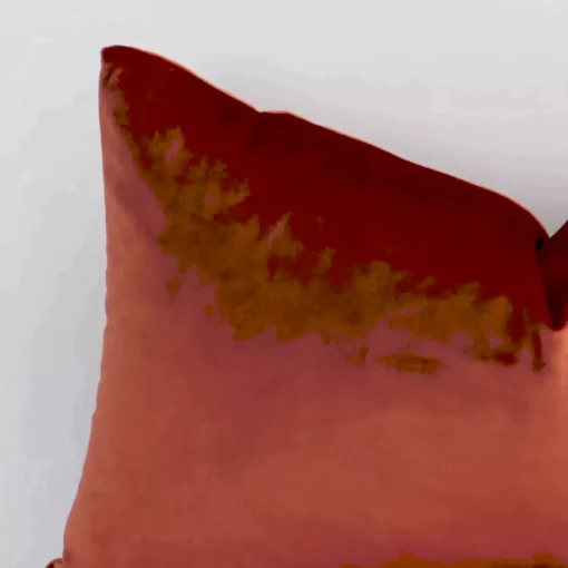 A rust velvet cushion cover’s corner is shown in more detail. It is possible to see the corner of a rectangular design and solid colour finish in much more detail.