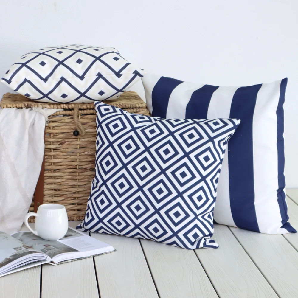 A scene showing a tea cup, novel and basket next to some square outdoor cushions.