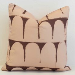 Sienna outdoor cushion with repeating arch pattern in warm brown on peach background.