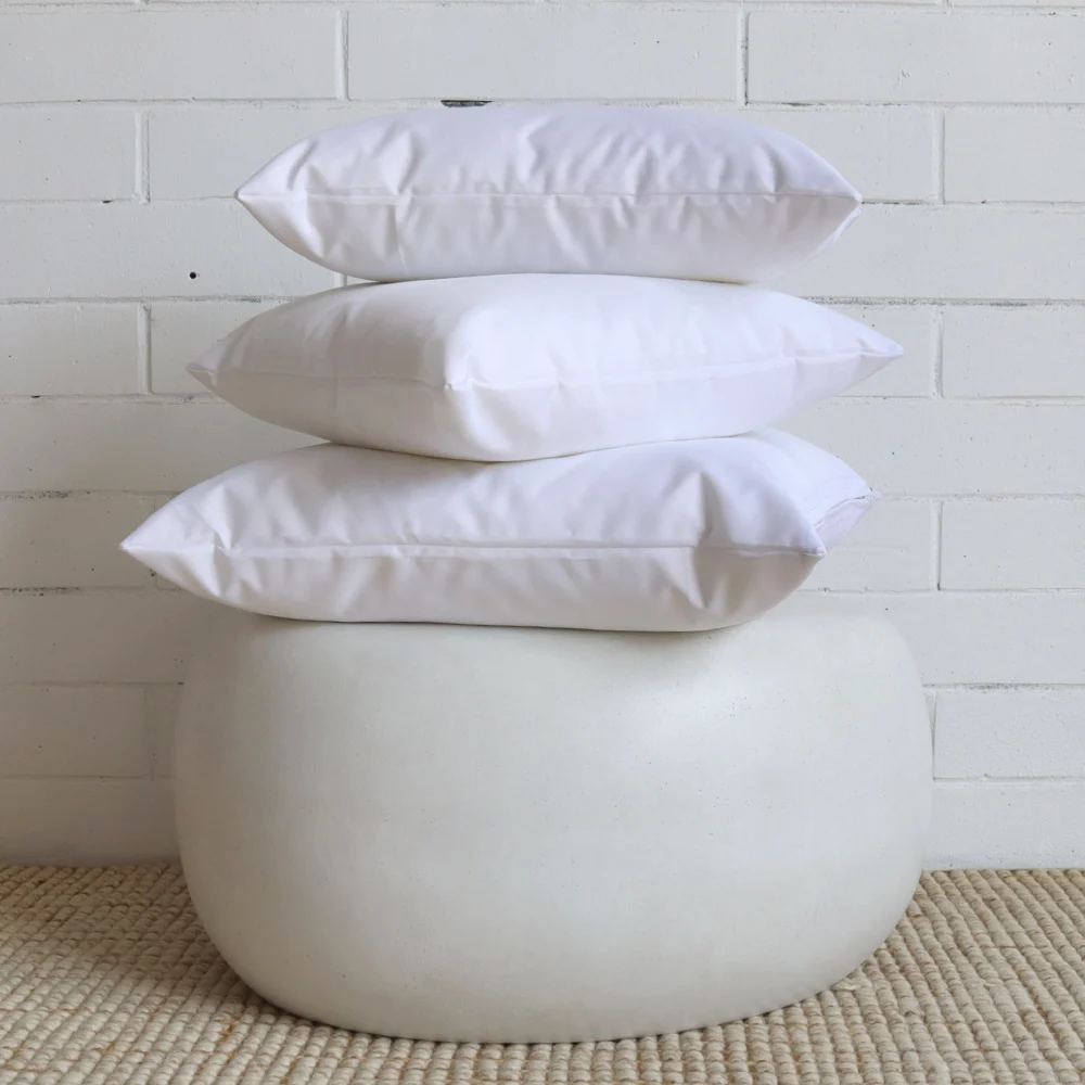 A small round table with a stack of white outdoor cushions placed upon it.
