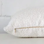 Side shot showing the seam of this rectangle white cushion that features a boucle material.