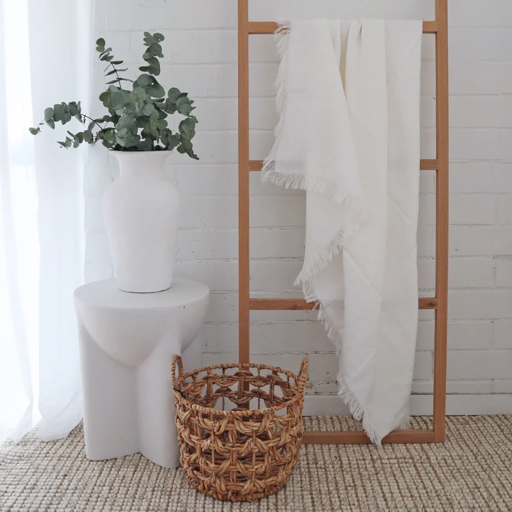 A timber hanging frame stands tall with a throw blanket draped over it.
