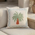 Tropica palm motif cushion with blue border and orange tree on sofa.