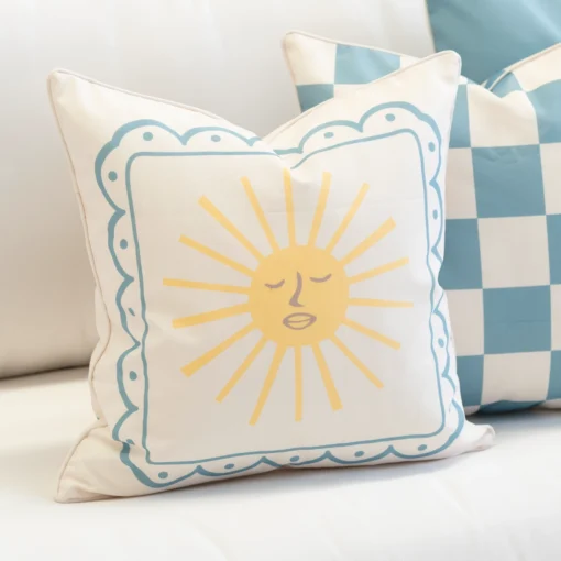 Tropica cushion with sun face design and blue scalloped border.