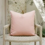 Tropica pink cushion with plain design on woven chair in outdoor setting.