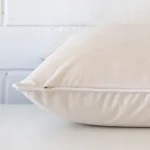 A white cushion cover is laid flat. This angle shows the side of the velvet fabric and its large shape.
