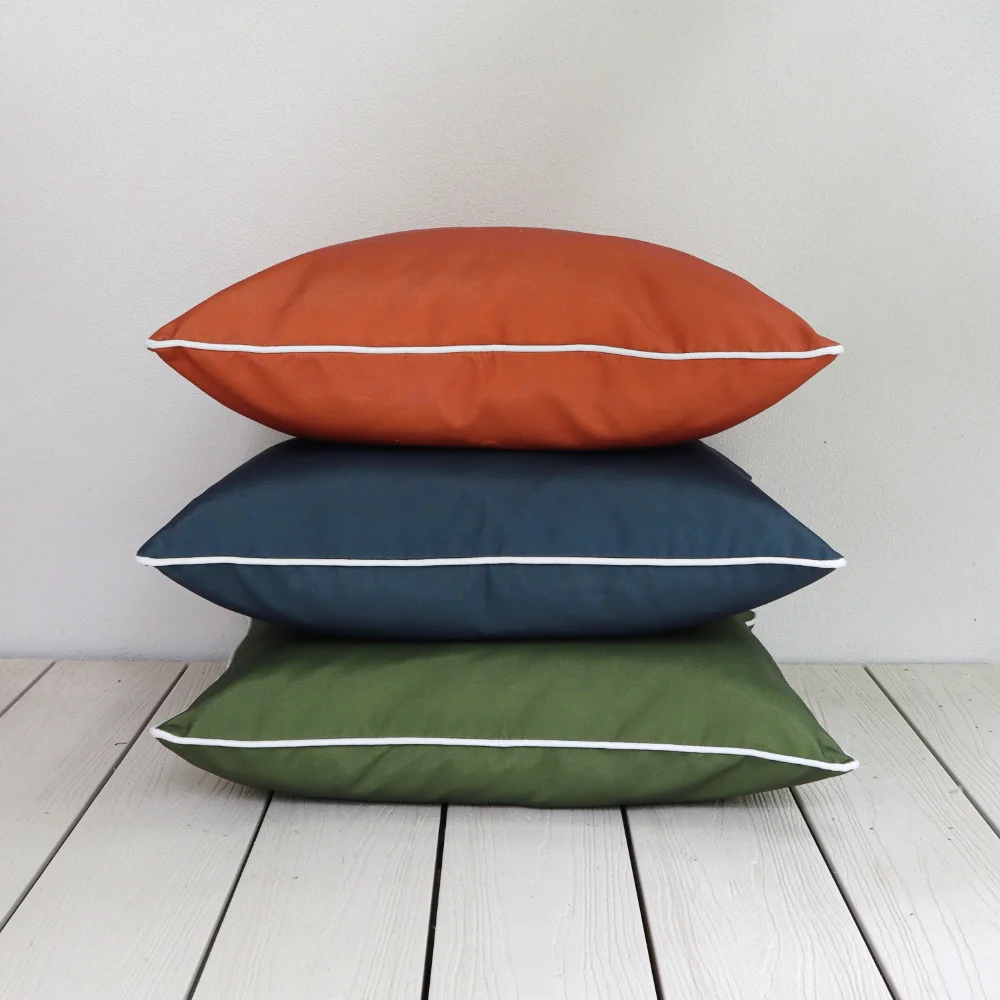 A white wall has large outdoor cushions stacked in front of it.